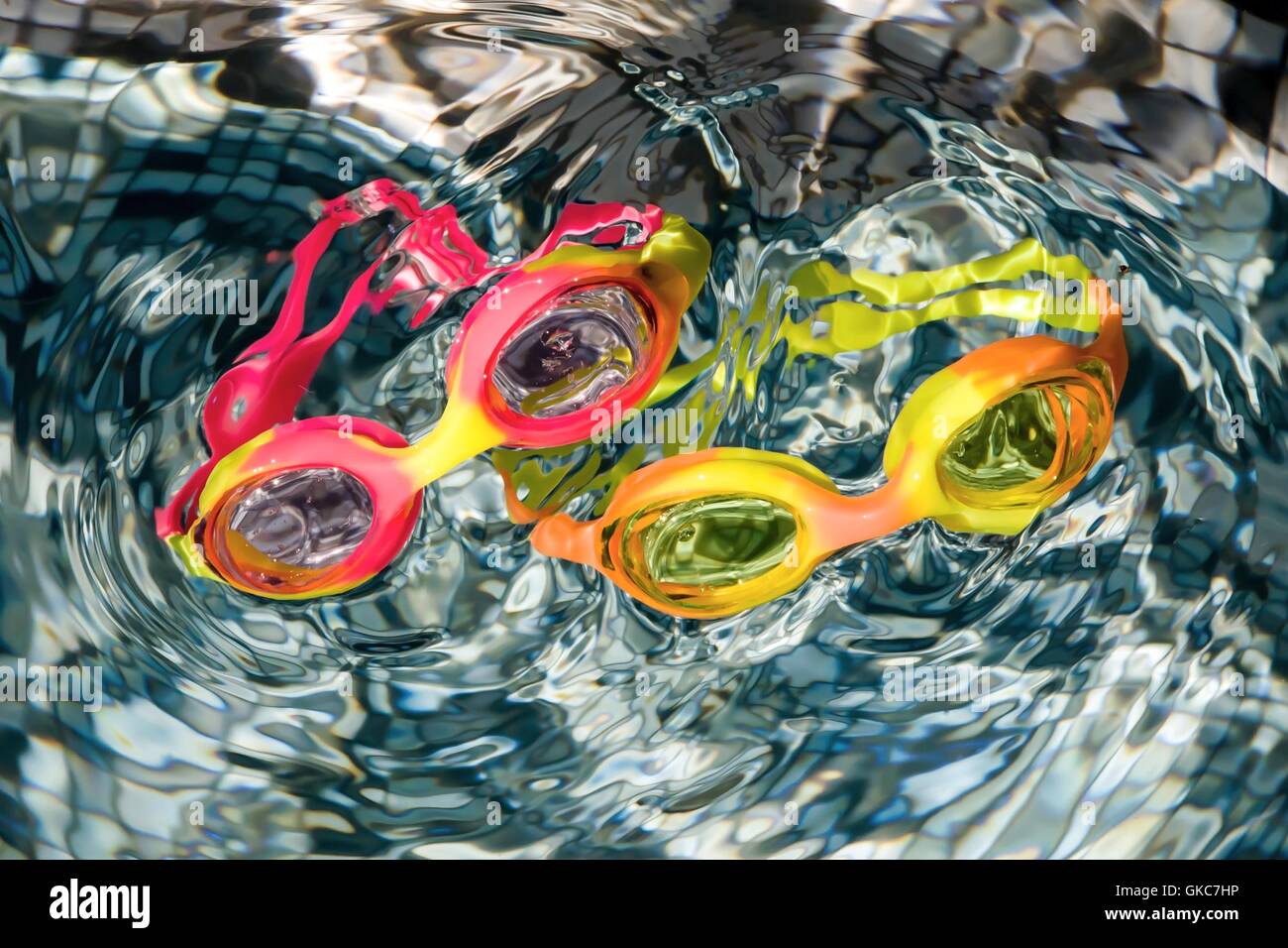Two very colorful swimming goggles floating in swimming pool to create a beautiful abstract image. Ideal for large print. Stock Photo