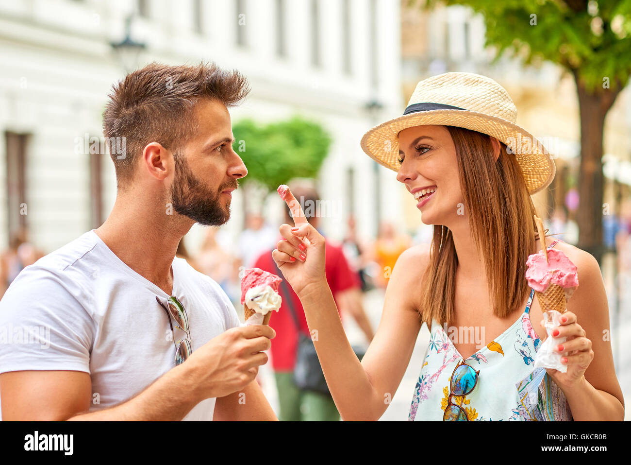 A beautiful young women is putting ice-cream with her finger on her boyfriend’s nose on the street of Budapest, Hungary. Stock Photo
