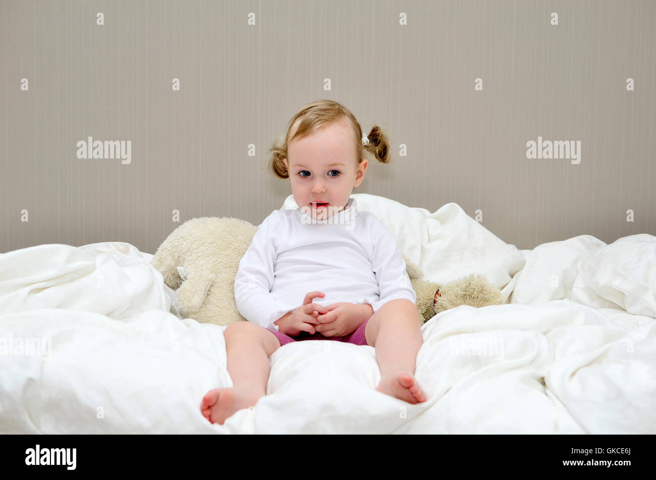 little girl sitting on a bed Stock Photo - Alamy