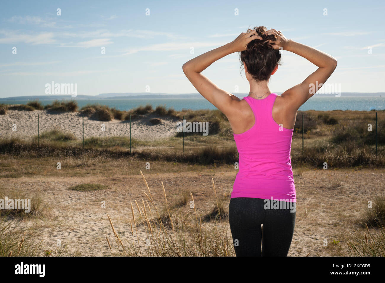 looking out to sea adjusting her hair after exercising and keeping fit Stock Photo