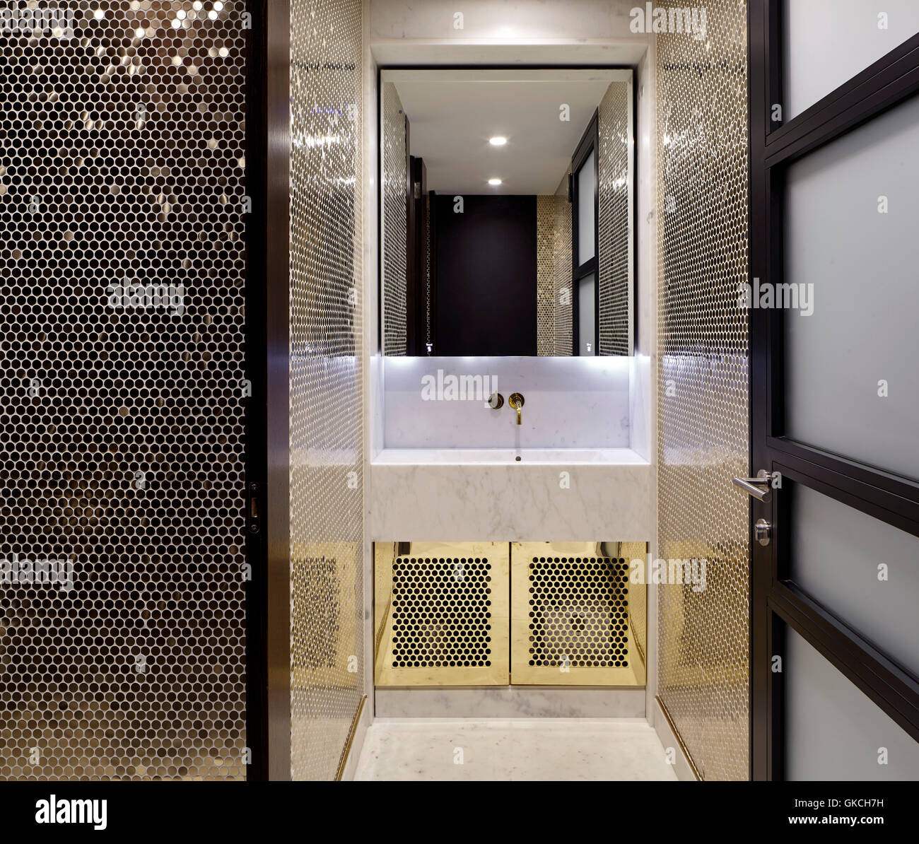 Mirror and wash basin detail in gold tiled bathroom. 54 Brooks Mews, London, United Kingdom. Architect: Stiff + Trevillion Architects, 2016. Stock Photo