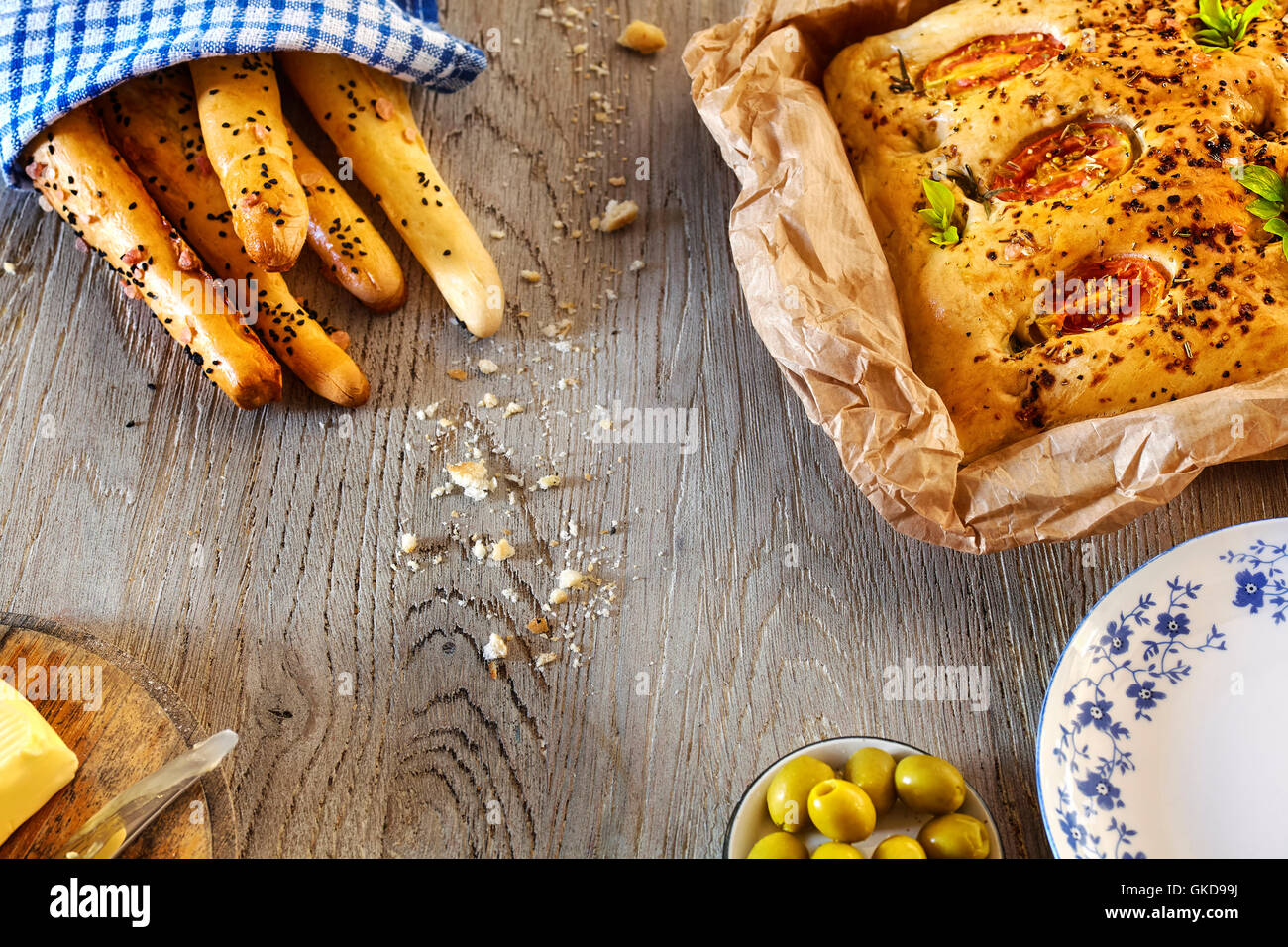 Traditional focaccia and bread sticks, rustic setting on a wooden table from above. Stock Photo