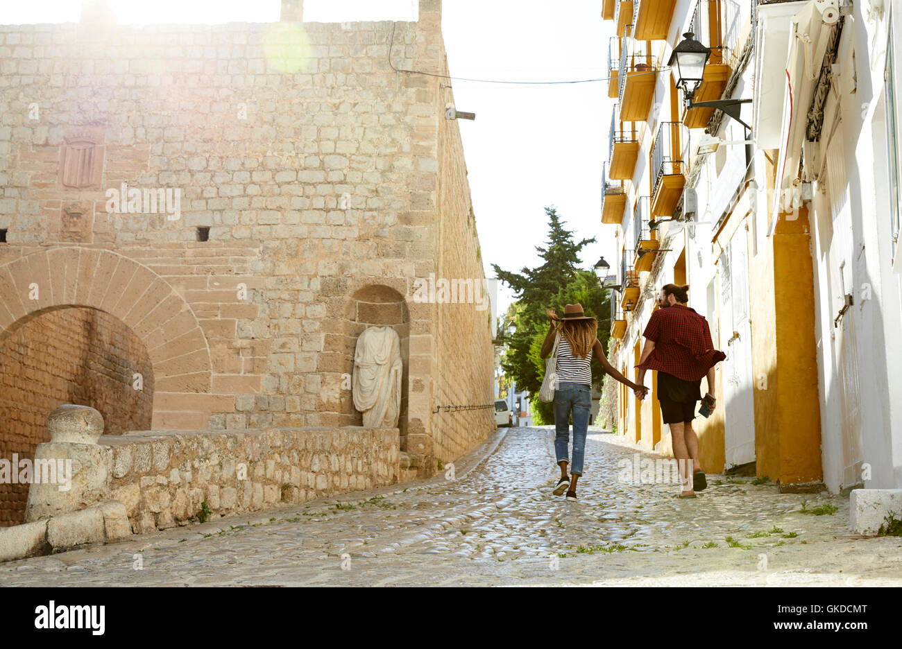 Couple on holiday hold hands walking in Ibiza, back view Stock Photo