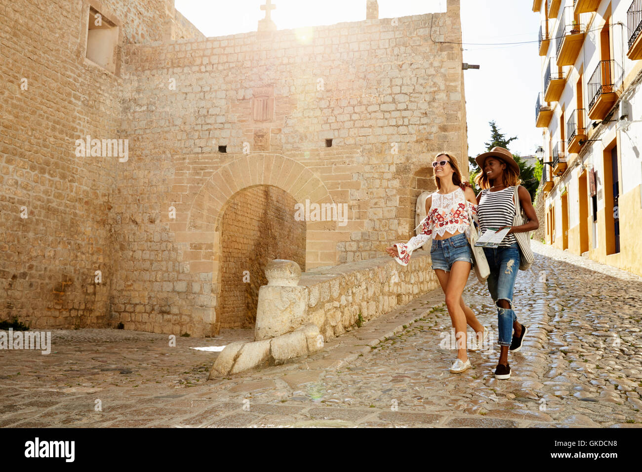 Two female friends on holiday walking with guidebook, Ibiza Stock Photo