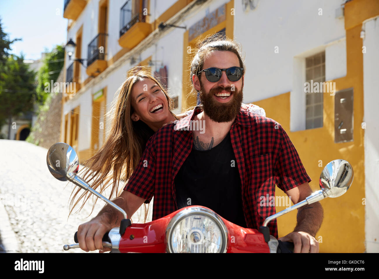 Couple sitting on a motor scooter laughing, Ibiza, Spain Stock Photo