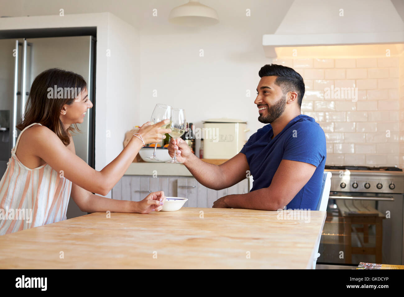 Adult couple drinking wine make a toast in the kitchen Stock Photo