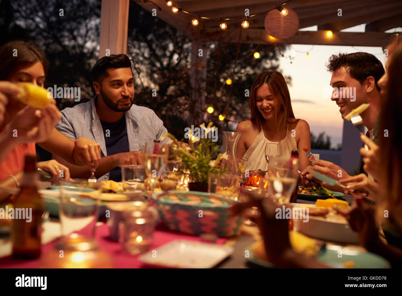 Friends eat and talk at a dinner party on a patio, close up Stock Photo