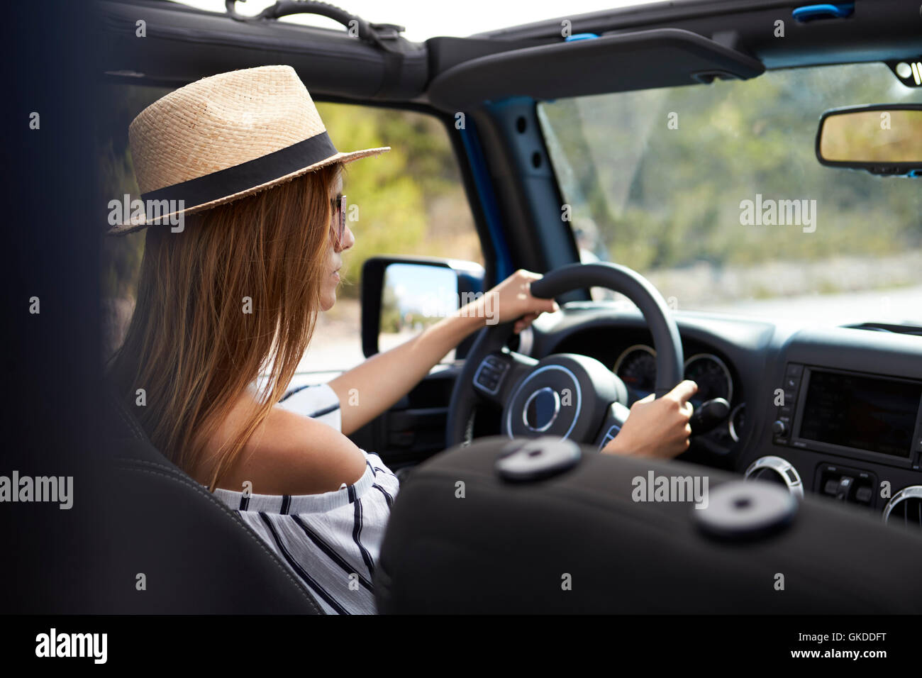 Young Woman Driving Open Top Car On Country Road Stock Photo