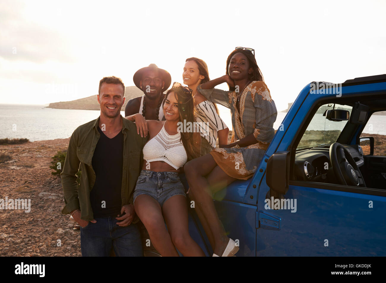 Portrait Of Friends Standing By Open Top Car On Cliffs Stock Photo