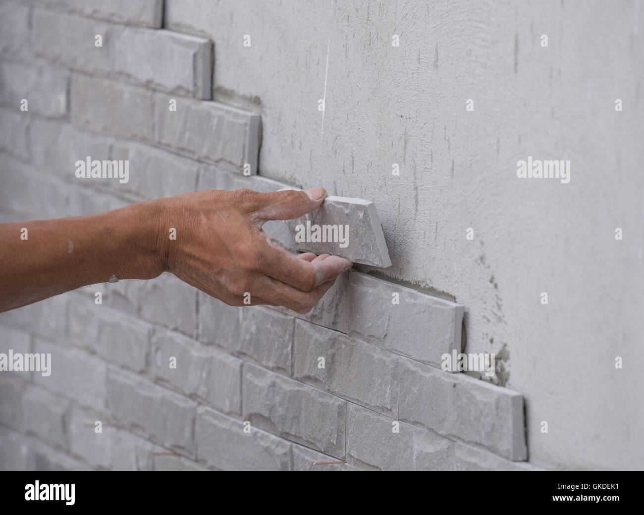 worker install stone wall tile with cement for house decoration Stock