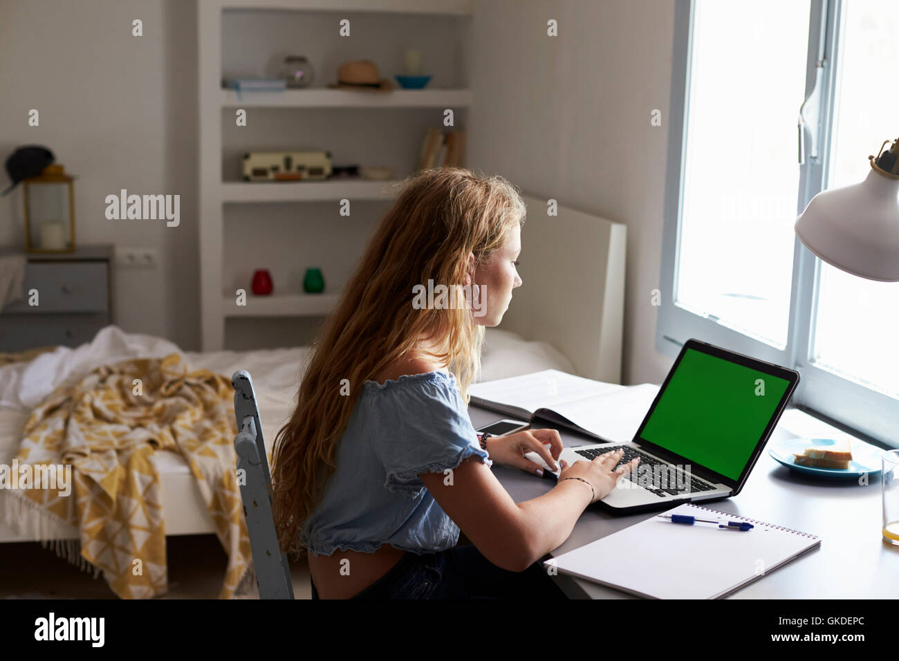 Teenage girl using laptop computer at a desk in her bedroom Stock Photo