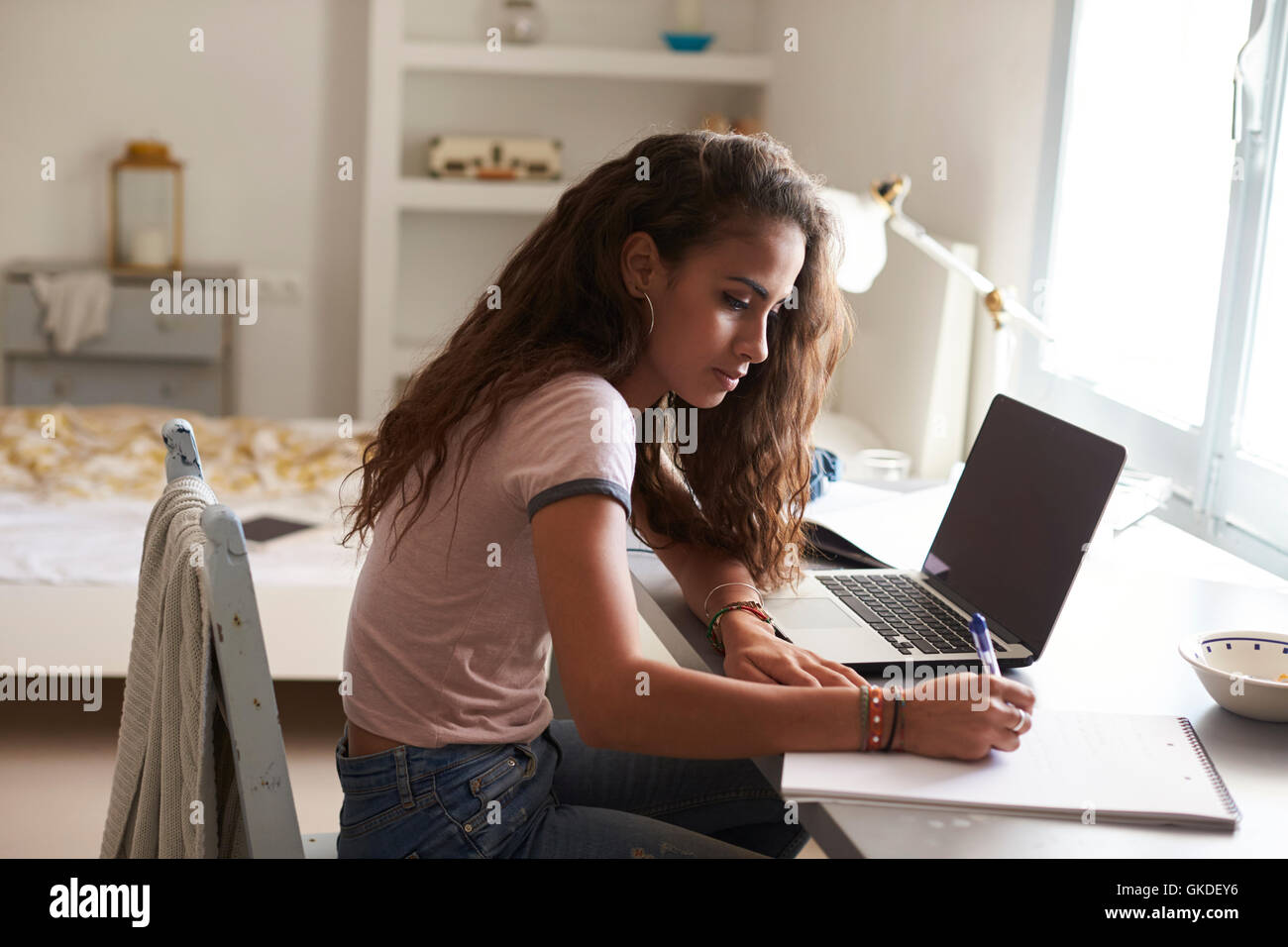 Teenage Girl Doing Homework At A Desk In Her Bedroom Stock Photo
