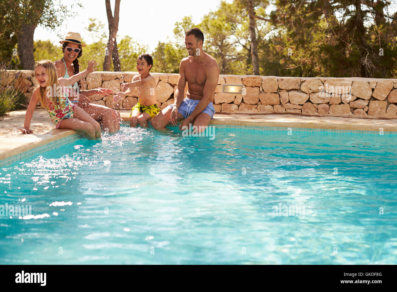 Wide Angle View Of Family On Vacation Having Fun By Pool Stock Photo
