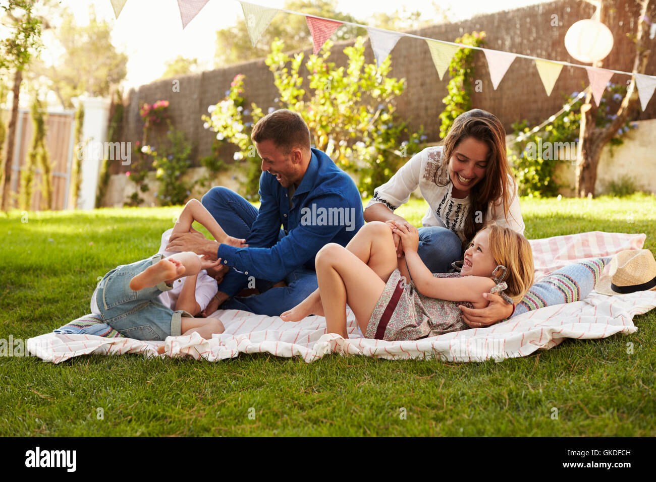 Parents Playing Game With Children On Blanket In Garden Stock Photo