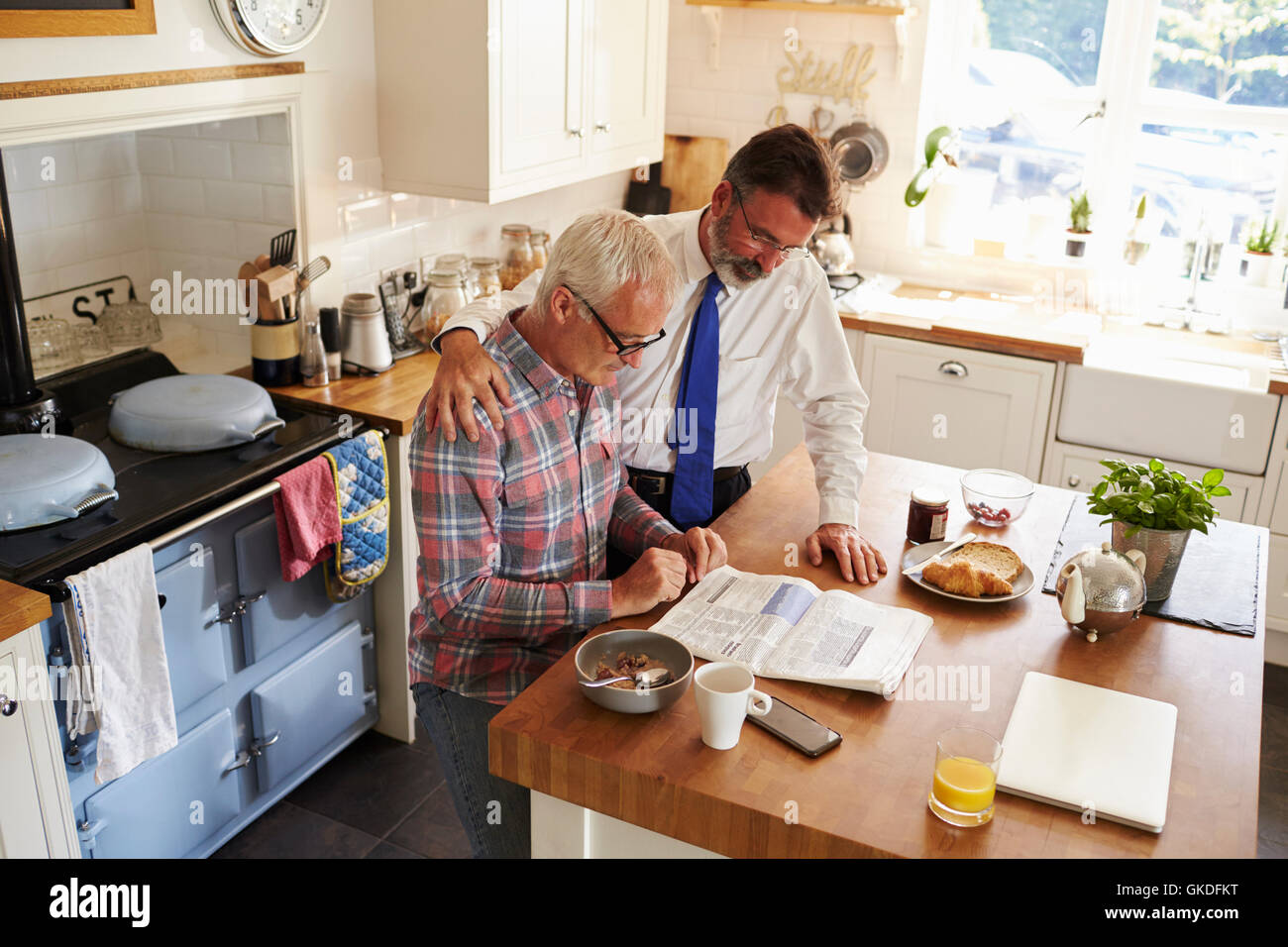 Male couple reading paper together in kitchen, elevated view Stock Photo
