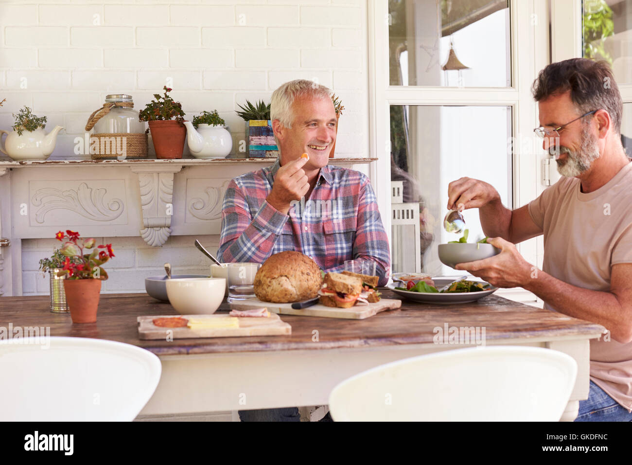 Girl eating lunch on patio with her gay male parents Stock Photo