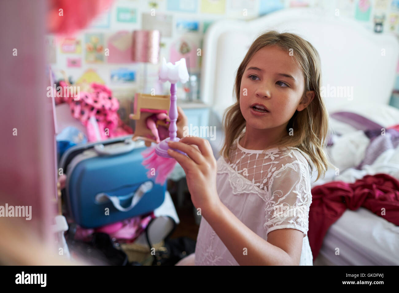 Young Girl Playing With Dolls House In Bedroom Stock Photo