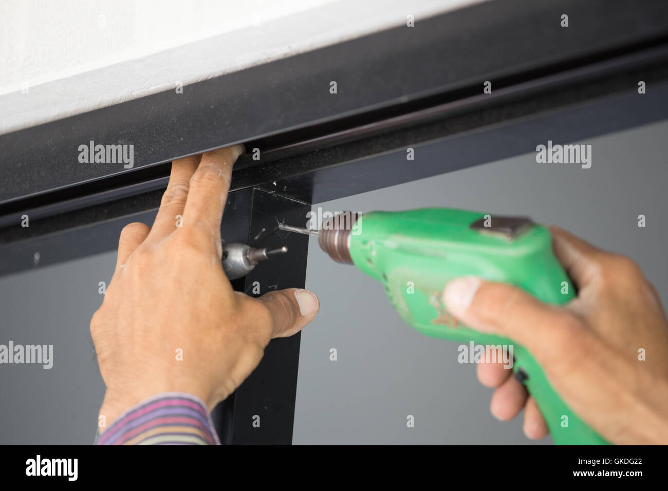 Close up of worker drilling holes in aluminium construction frame with