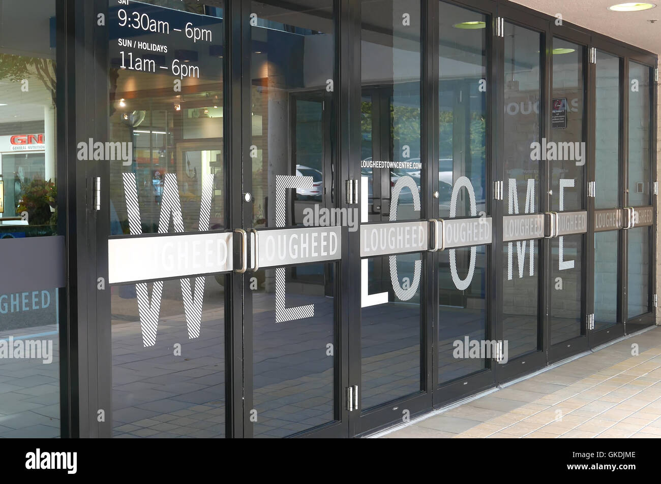 One side of mall entrance with welcome sign on door in Lougheed Town Centre mall Stock Photo