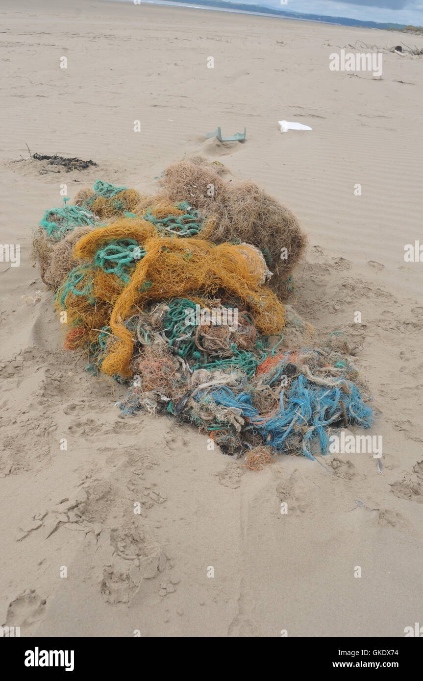 old rope from shipping washed up on a sandy beach, environmental concerns danger to wildlife Stock Photo