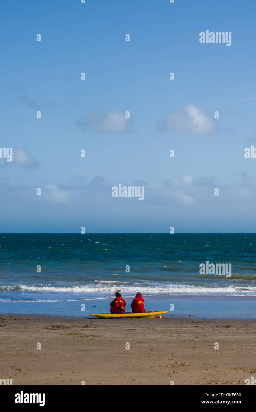 A serene image of Tenby beach showing two lone lifeguards keeping a watch on the waters. Stock Photo