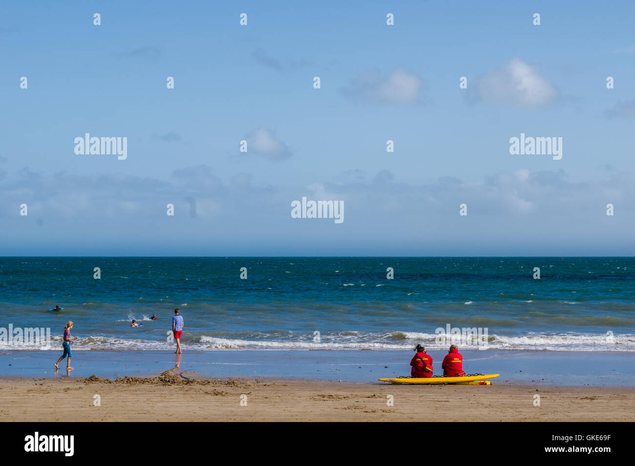 A serene image of Tenby beach showing two lifeguards, sat down, keeping a watch on the surf, the waters and also the swimmers Stock Photo
