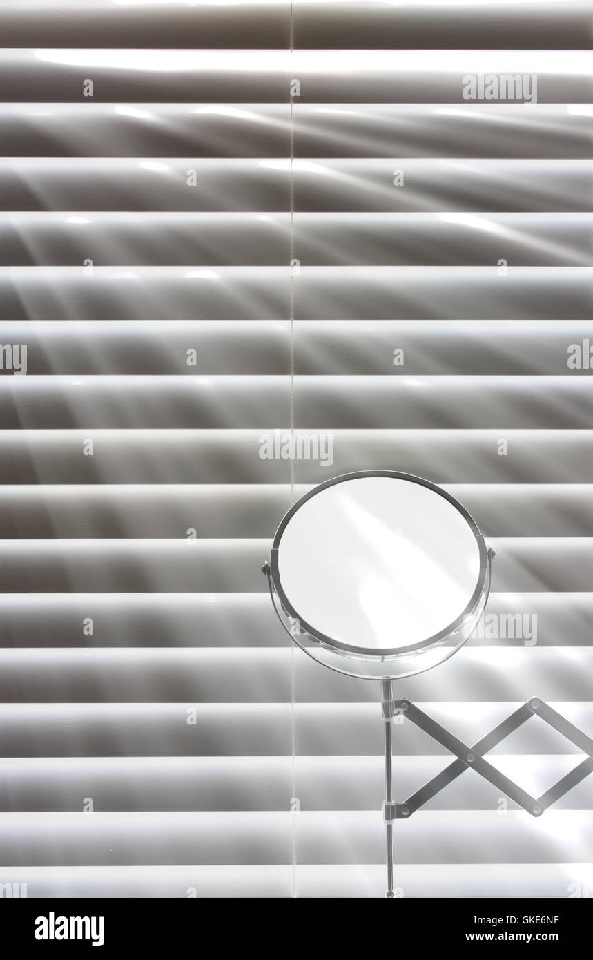 Shaving mirror infront of bathroom blinds Stock Photo