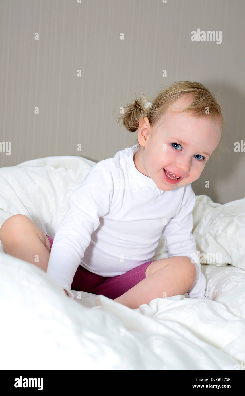 little girl sitting on a bed and smiling Stock Photo - Alamy