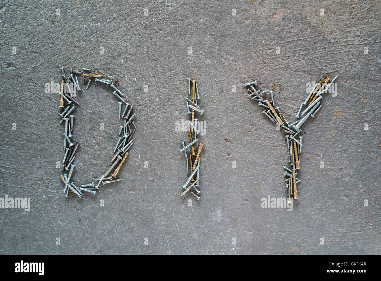 DIY word composed of screws and bolts on a cement surface. Top view, Stock Photo