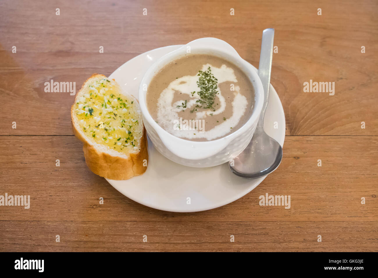 Puree mushroom soup in white bowl with garlic bread on wooden table. Stock Photo