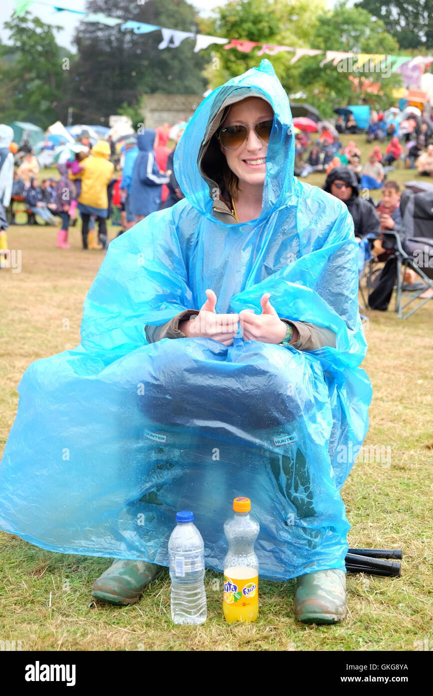 Green Man Festival, Crickhowell, Wales  - August 2016 - A young female fan enjoys the music festival wrapped in her plastic poncho after a day of heavy showers. Stock Photo