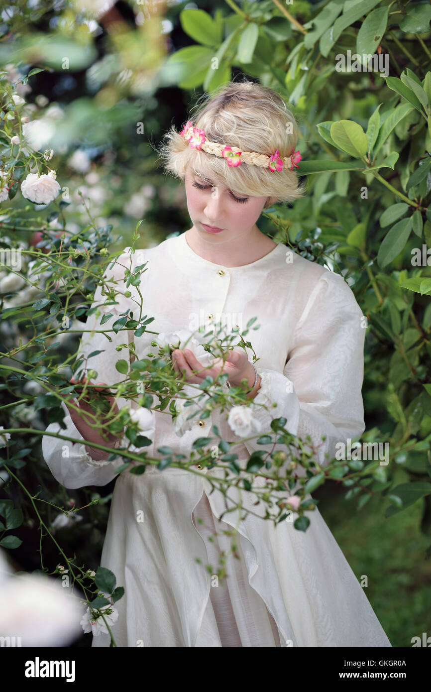 Fair young woman with white roses . Dreamy garden Stock Photo