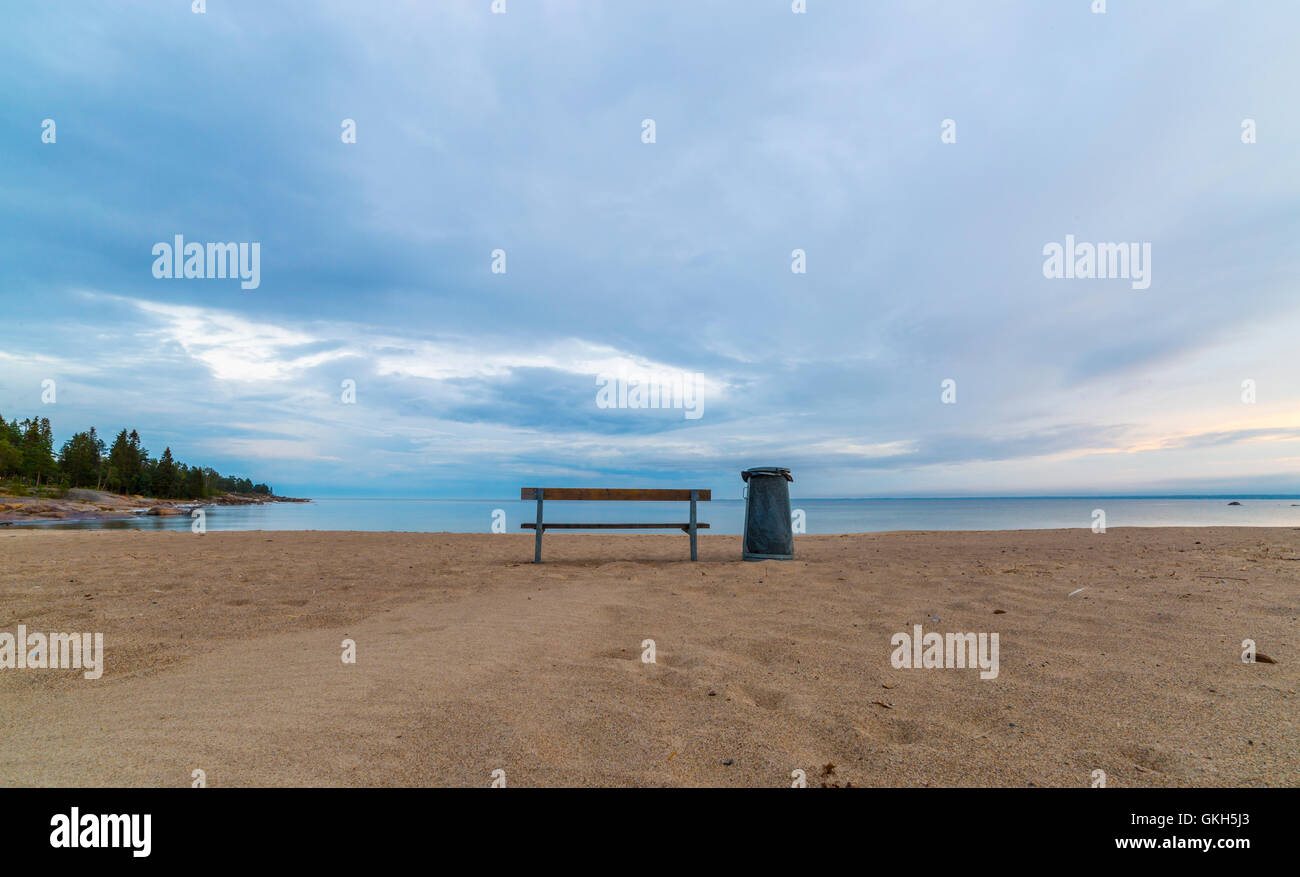 Bench and Trash Can on Beach by Ocean. Stock Photo