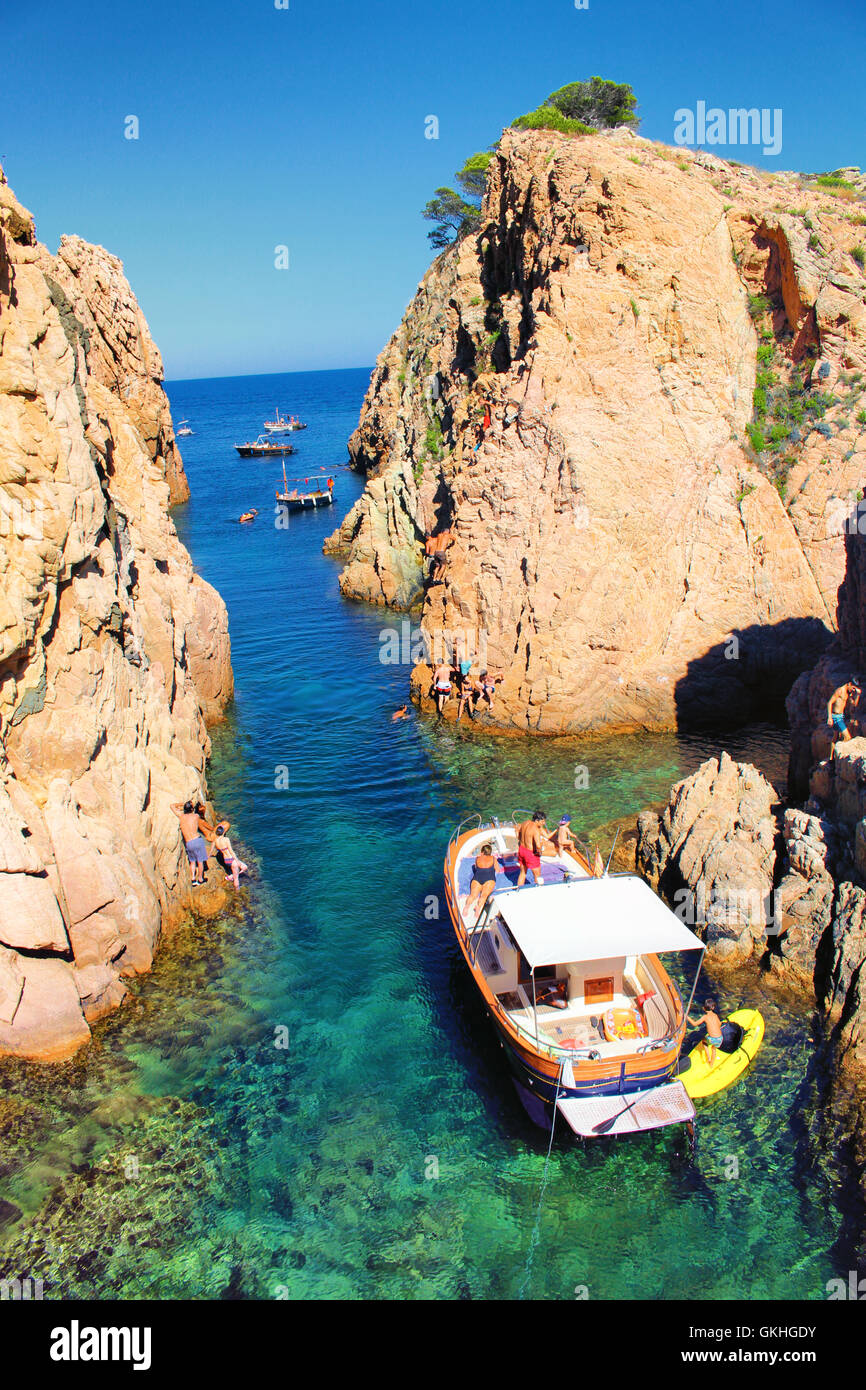GIRONA/SPAIN - 13 AUGUST 2016: People enyojing mid-august weekend on a boat in a small bay with transparent green waters in Cala Stock Photo