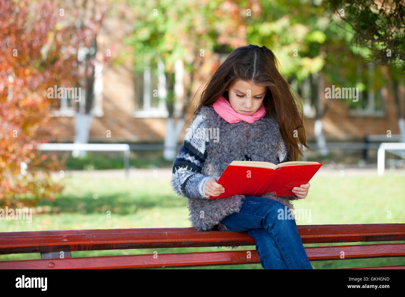 Beautiful little girl sitting on a bench in autumn park Stock Photo - Alamy