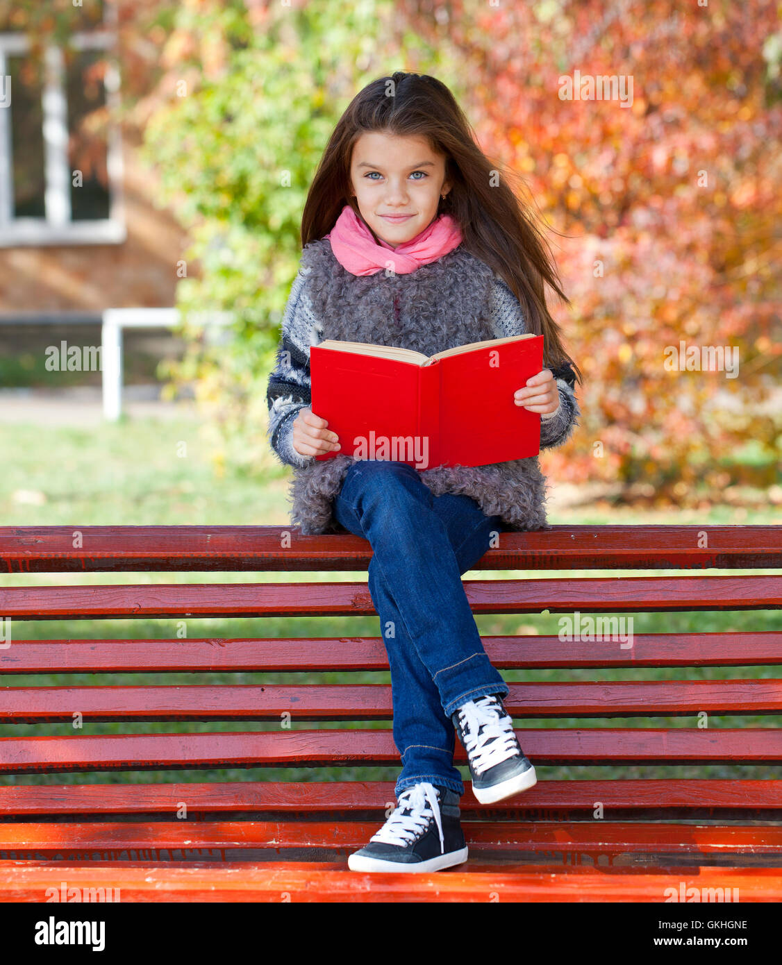 Beautiful little girl sitting on a bench in autumn park Stock Photo - Alamy