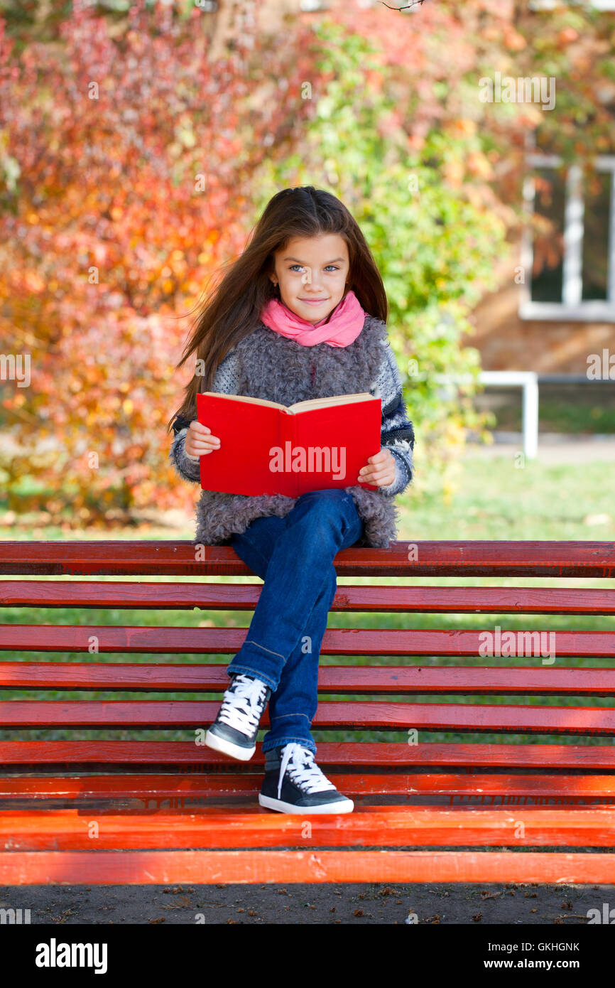 Beautiful little girl sitting on a bench in autumn park Stock Photo - Alamy