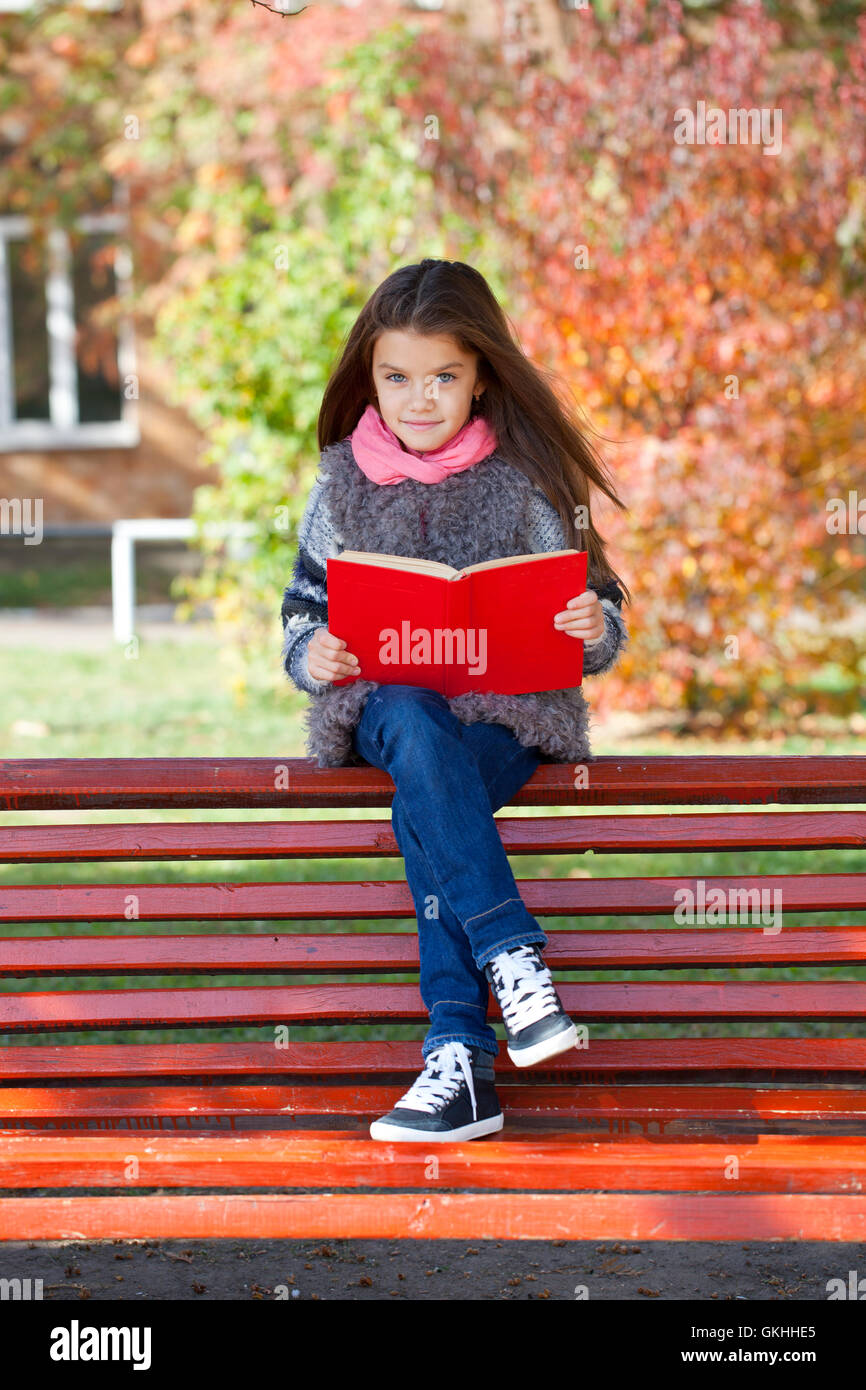 Beautiful little girl sitting on a bench in autumn park Stock Photo - Alamy