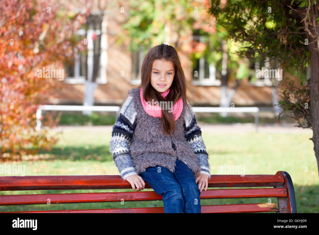 Beautiful little girl sitting on a bench in autumn park Stock Photo - Alamy