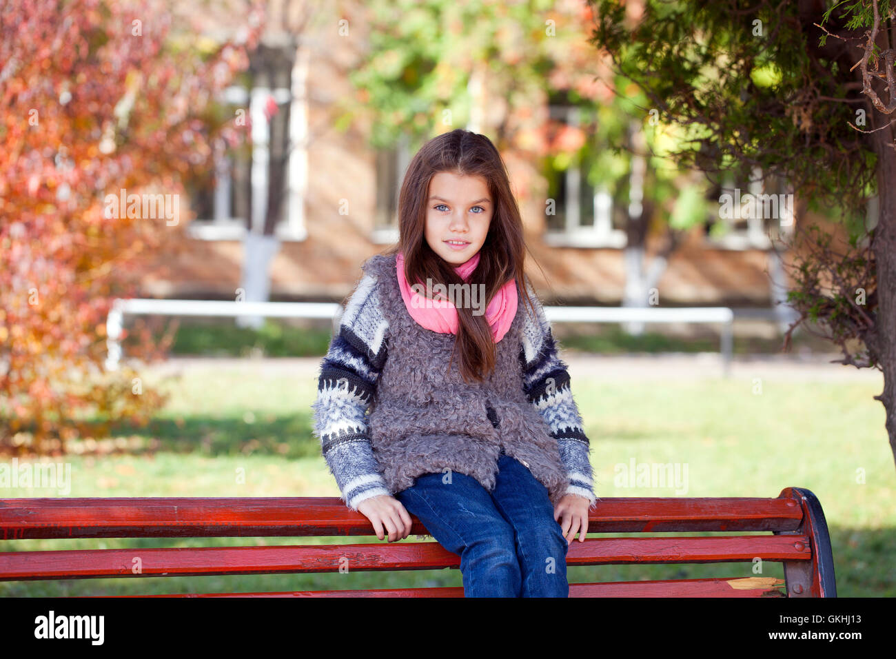 Beautiful little girl sitting on a bench in autumn park Stock Photo - Alamy
