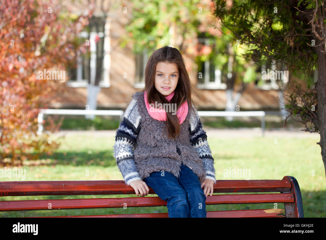 Beautiful little girl sitting on a bench in autumn park Stock Photo - Alamy
