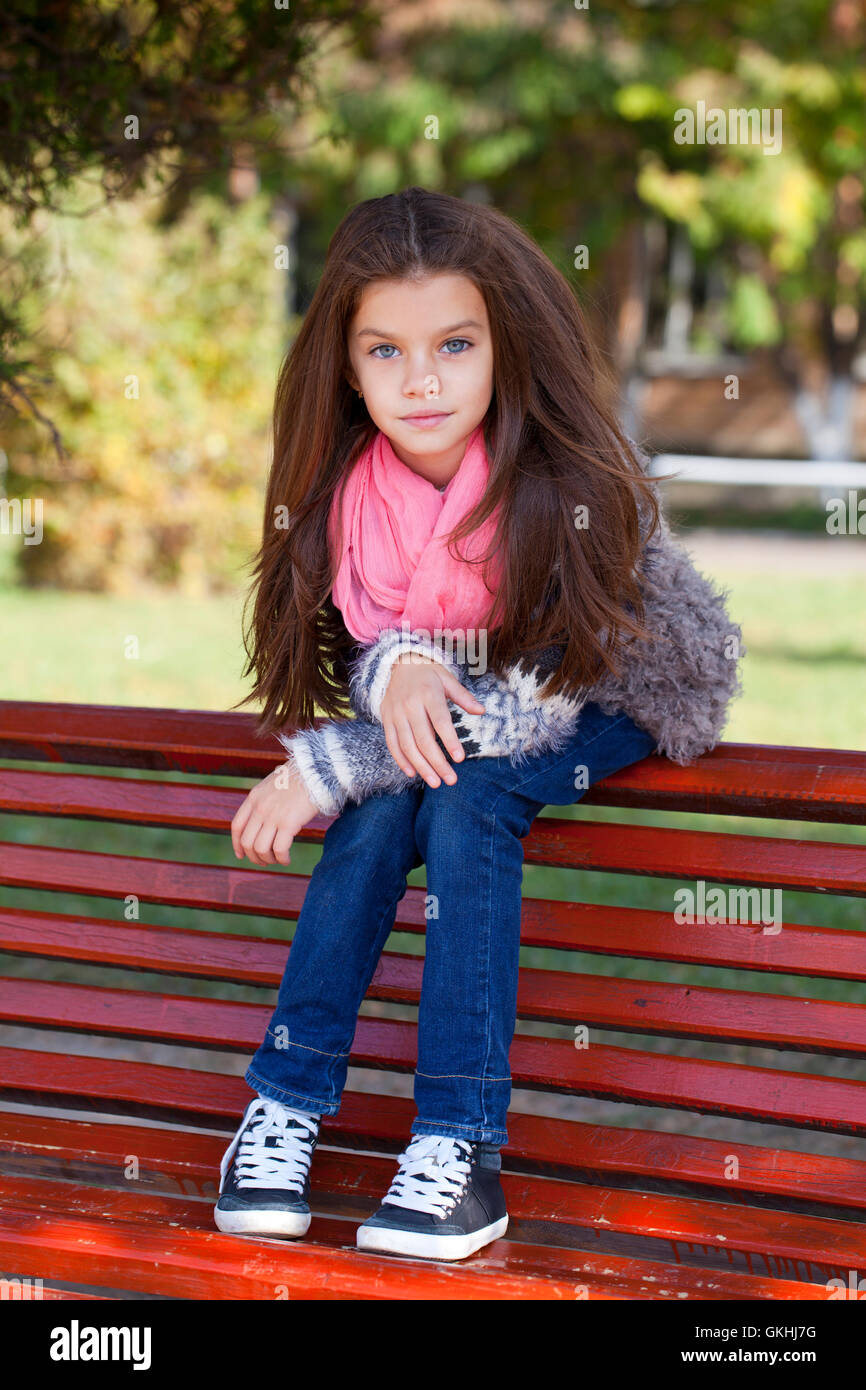 Beautiful little girl sitting on a bench in autumn park Stock Photo - Alamy