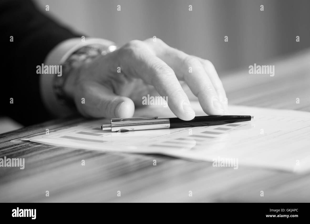 Man's hands holding a black pen in both arms in a thinking gesture during a meeting or negotiation Stock Photo