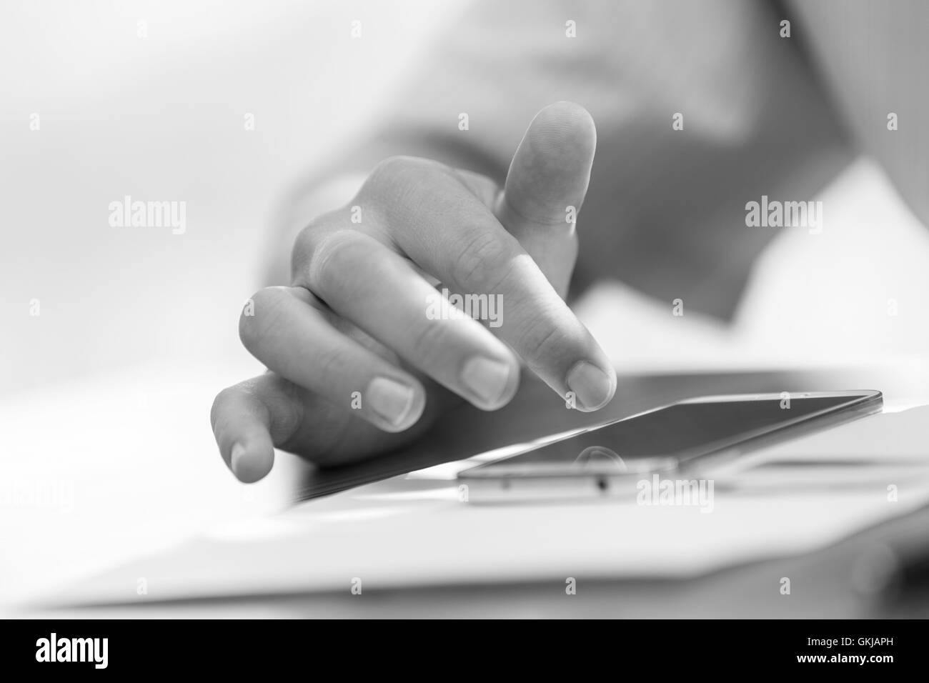 Male hand using smartphone gadget lying on a table. Black and white image Stock Photo