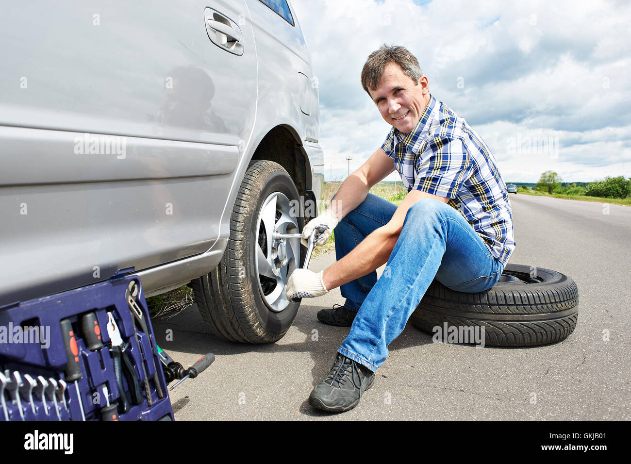 Man with jack changing a spare tire of car on road Stock Photo Alamy