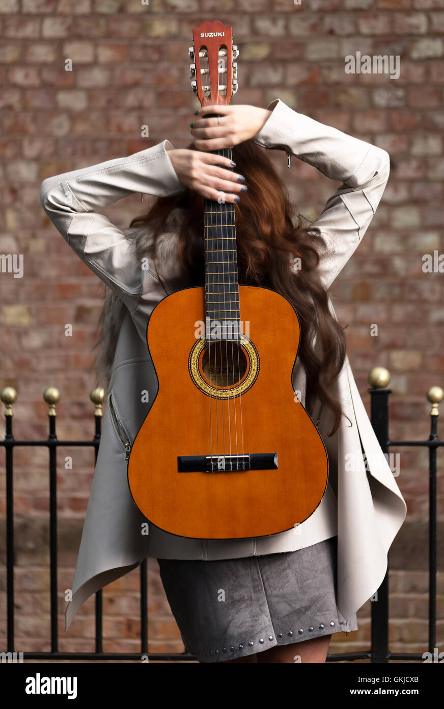 Country music star performer female, shot from rear, brick wall backdrop Stock Photo