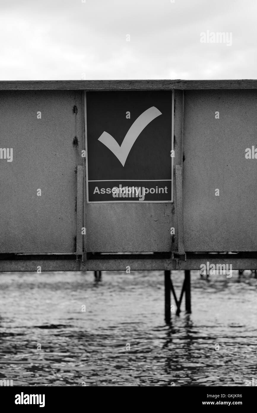 Assembly Point Sign on metal siding above water Stock Photo