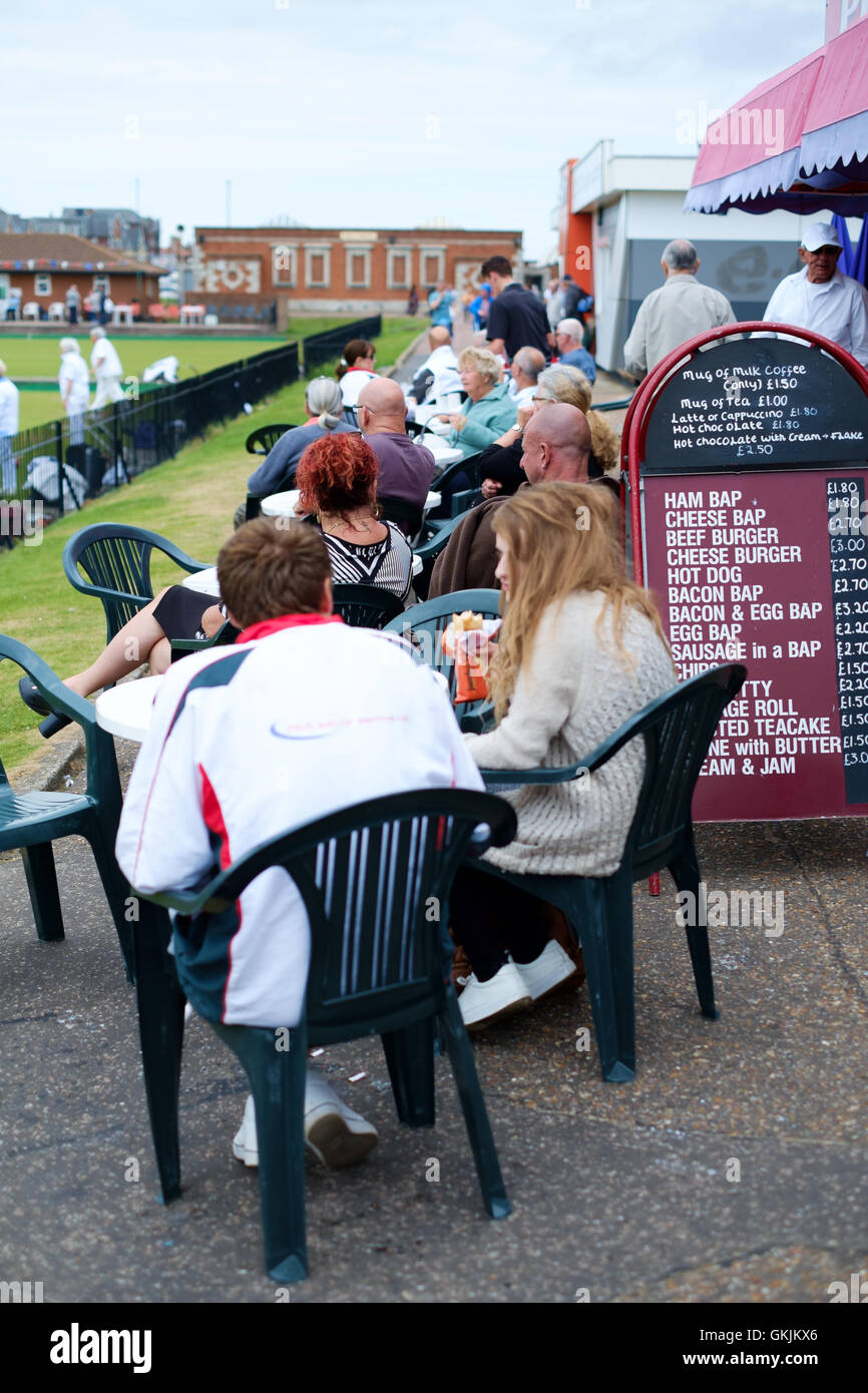 Holiday makers watching bowling outside cafe, Great Yarmouth Stock