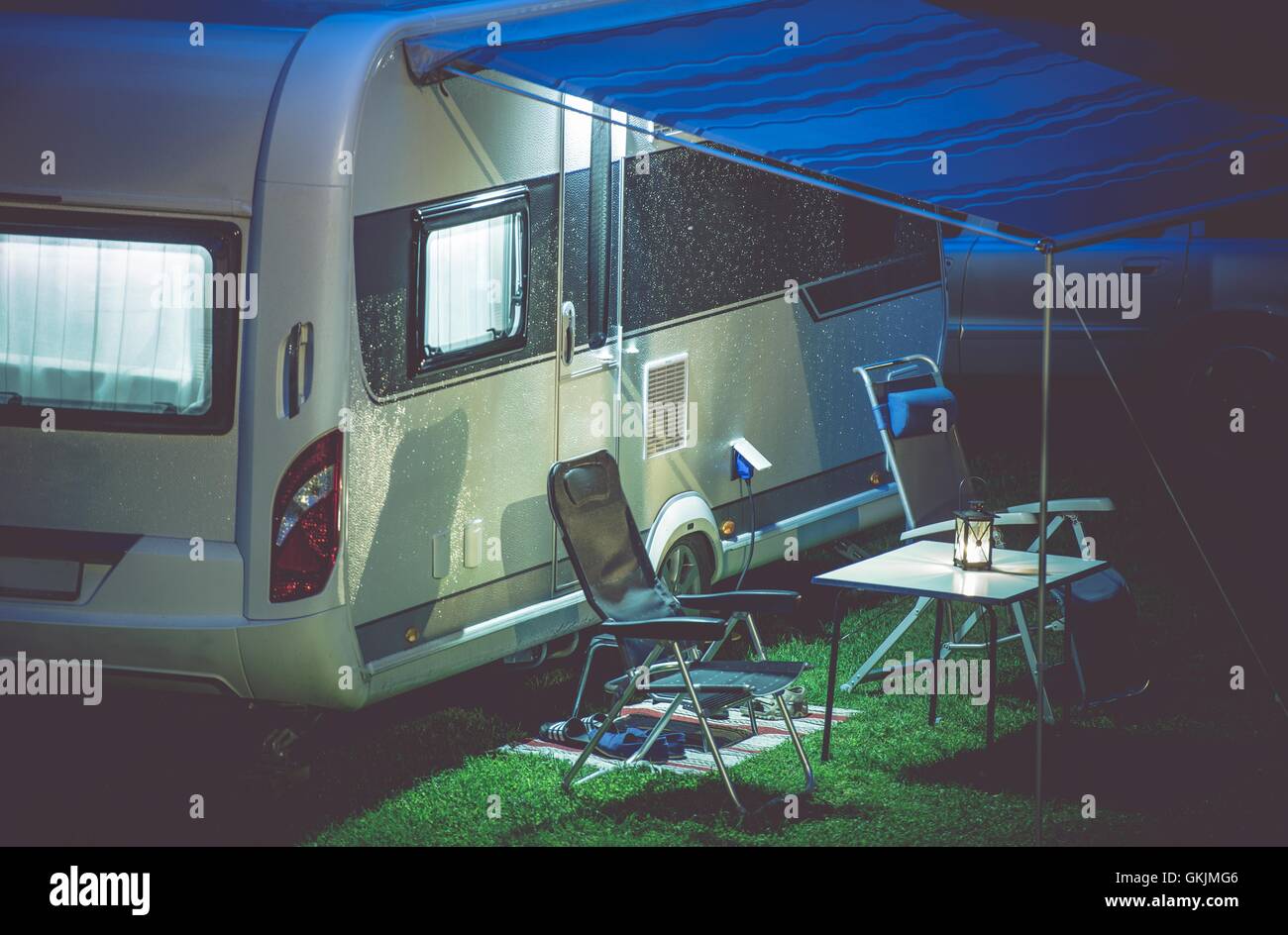 Travel Trailer Camping Romantic Setup. Modern Travel Trailer and Camping Furnitures Under the Awning. Modern Caravaning. Stock Photo
