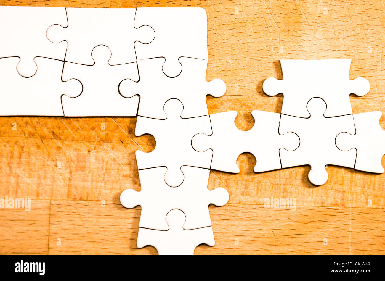white jigsaw/puzzle over  a wooden table background, symbol of problem solving Stock Photo